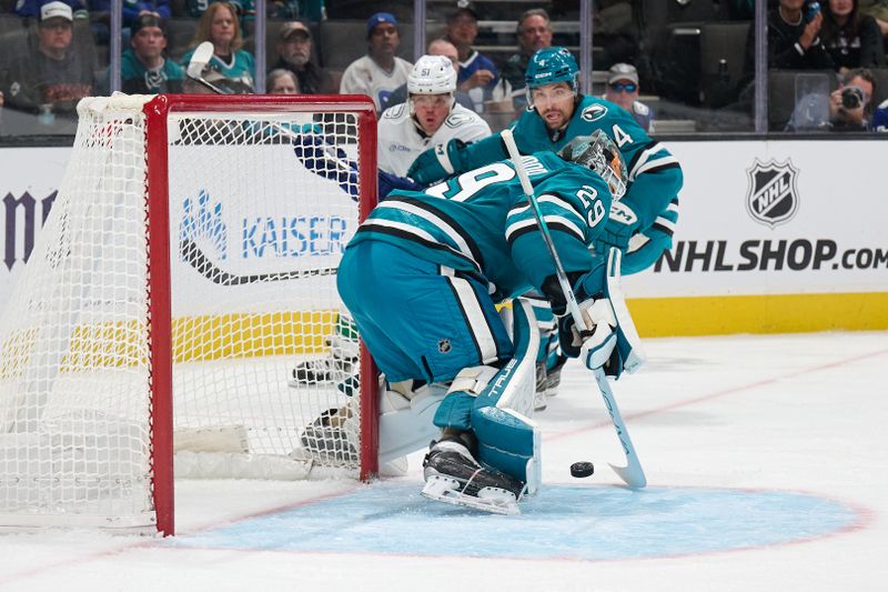 Nov 2, 2024; San Jose, California, USA; San Jose Sharks goaltender Mackenzie Blackwood (29) and defenseman Cody Ceci (4) defend the puck against Vancouver Canucks defenseman Mark Friedman (51) during the first period at SAP Center at San Jose. Mandatory Credit: Robert Edwards-Imagn Images