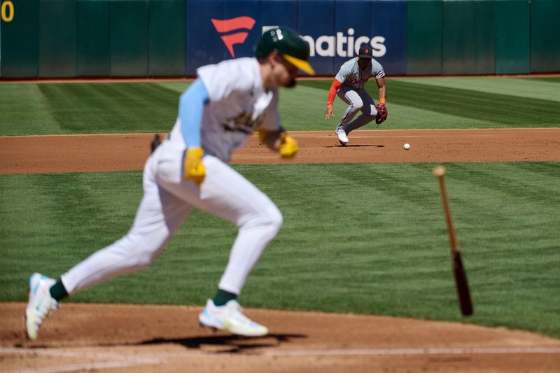Sep 7, 2024; Oakland, California, USA; Oakland Athletics infielder Zack Gelof (20) runs to first base and Detroit Tigers infielder Andy Ibanez (77) fields a ground ball during the second inning at Oakland-Alameda County Coliseum. Mandatory Credit: Robert Edwards-Imagn Images