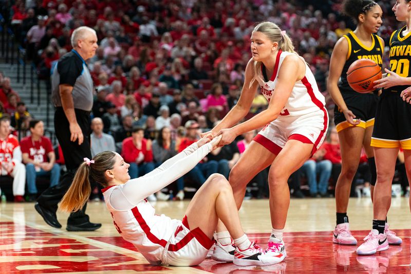 Feb 11, 2024; Lincoln, Nebraska, USA; Nebraska Cornhuskers guard Kendall Moriarty (15) is helped up by forward Natalie Potts (22) against the Iowa Hawkeyes during the second quarter at Pinnacle Bank Arena. Mandatory Credit: Dylan Widger-USA TODAY Sports