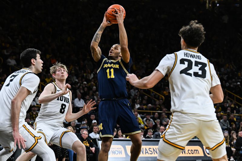 Mar 5, 2026; Iowa City, Iowa, USA; Michigan Wolverines guard Roddy Gayle Jr. (11) goes to the basket as Iowa Hawkeyes guard Isaia Howard (23) and forward Cooper Koch (8) and forward Alvaro Folgueiras (7) defend during the first half at Carver-Hawkeye Arena. Mandatory Credit: Jeffrey Becker-Imagn Images