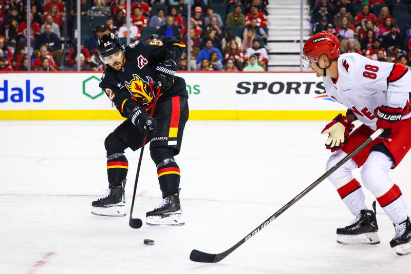 Oct 24, 2024; Calgary, Alberta, CAN; Calgary Flames defenseman MacKenzie Weegar (52) passes the puck against Carolina Hurricanes center Martin Necas (88) during the first period at Scotiabank Saddledome. Mandatory Credit: Sergei Belski-Imagn Images