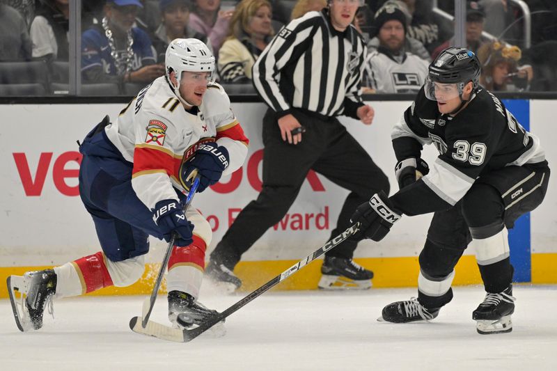 Nov 6, 2025; Los Angeles, California, USA; Florida Panthers right wing Mackie Samoskevich (11) is defended by Los Angeles Kings left wing Jeff Malott (39) as he passes the puck during the second period at Crypto.com Arena. Mandatory Credit: Jayne Kamin-Oncea-Imagn Images