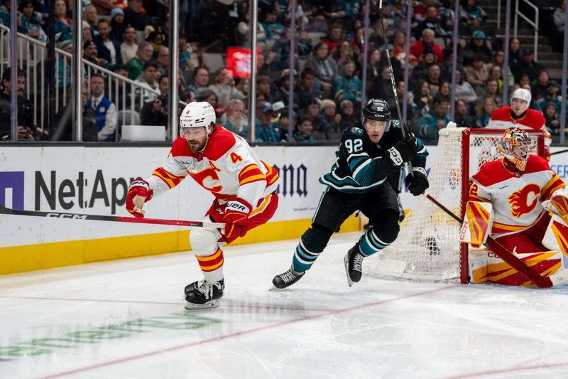 Dec 16, 2025; San Jose, California, USA; Calgary Flames defenseman Rasmus Andersson (4) and San Jose Sharks left wing Igor Chernyshov (92) chase the puck during the second period at SAP Center at San Jose. Mandatory Credit: Neville E. Guard-Imagn Images