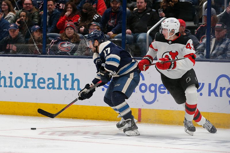 Jan 19, 2024; Columbus, Ohio, USA; Columbus Blue Jackets right wing Justin Danforth (17) skates the puck away from New Jersey Devils defenseman Luke Hughes (43) during the third period at Nationwide Arena. Mandatory Credit: Russell LaBounty-USA TODAY Sports