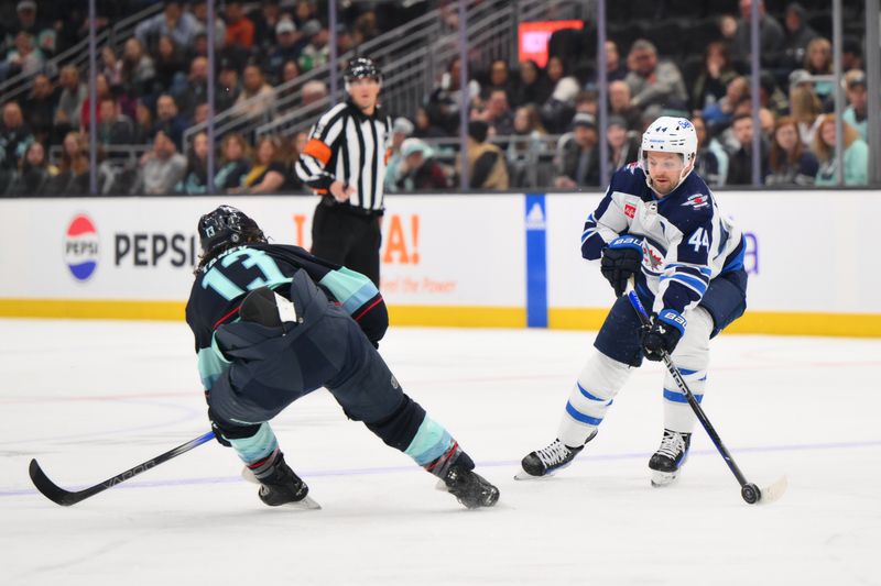 Mar 8, 2024; Seattle, Washington, USA; Winnipeg Jets defenseman Josh Morrissey (44) plays the puck while defended by Seattle Kraken left wing Brandon Tanev (13) during the first period at Climate Pledge Arena. Mandatory Credit: Steven Bisig-USA TODAY Sports