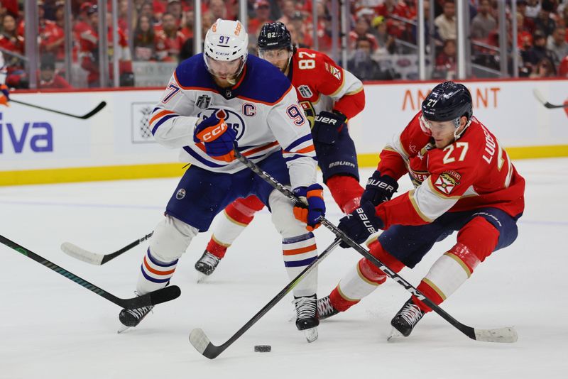 Jun 8, 2024; Sunrise, Florida, USA; Florida Panthers forward Eetu Luostarinen (27) reaches across Edmonton Oilers forward Connor McDavid (97) for the puck during the first period in game one of the 2024 Stanley Cup Final at Amerant Bank Arena. Mandatory Credit: Sam Navarro-USA TODAY Sports