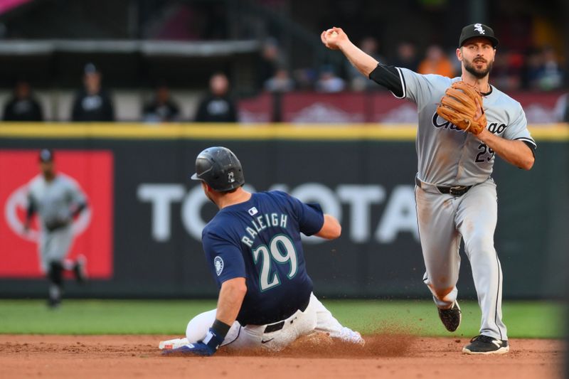 Jun 12, 2024; Seattle, Washington, USA; Chicago White Sox shortstop Paul DeJong (29) throws over Seattle Mariners catcher Cal Raleigh (29) to first base during the fourth inning at T-Mobile Park. Mandatory Credit: Steven Bisig-USA TODAY Sports