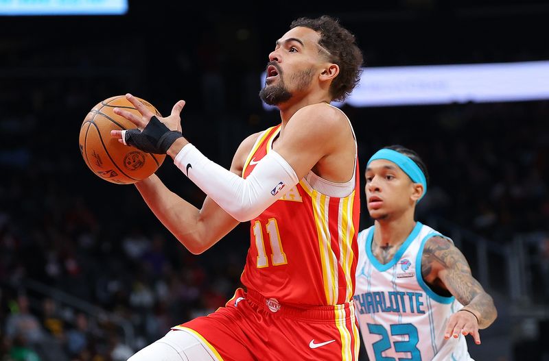 ATLANTA, GEORGIA - APRIL 10:  Trae Young #11 of the Atlanta Hawks drives to the basket against Tre Mann #23 of the Charlotte Hornets during the first quarter at State Farm Arena on April 10, 2024 in Atlanta, Georgia.  NOTE TO USER: User expressly acknowledges and agrees that, by downloading and/or using this photograph, user is consenting to the terms and conditions of the Getty Images License Agreement.  (Photo by Kevin C. Cox/Getty Images)