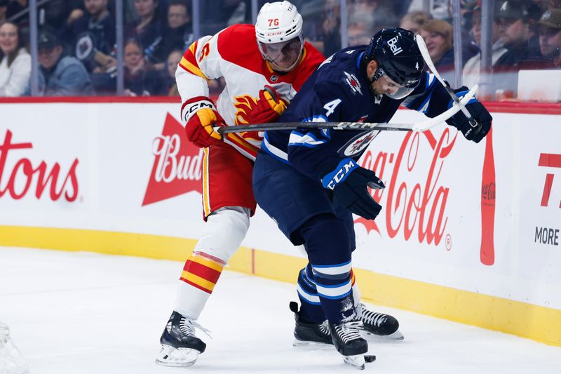 Sep 27, 2025; Winnipeg, Manitoba, CAN;  Winnipeg Jets defenseman Neal Pionk (4) shields the puck from Calgary Flames forward Martin Pospisil (76) during the first period at Canada Life Centre. Mandatory Credit: Terrence Lee-Imagn Images