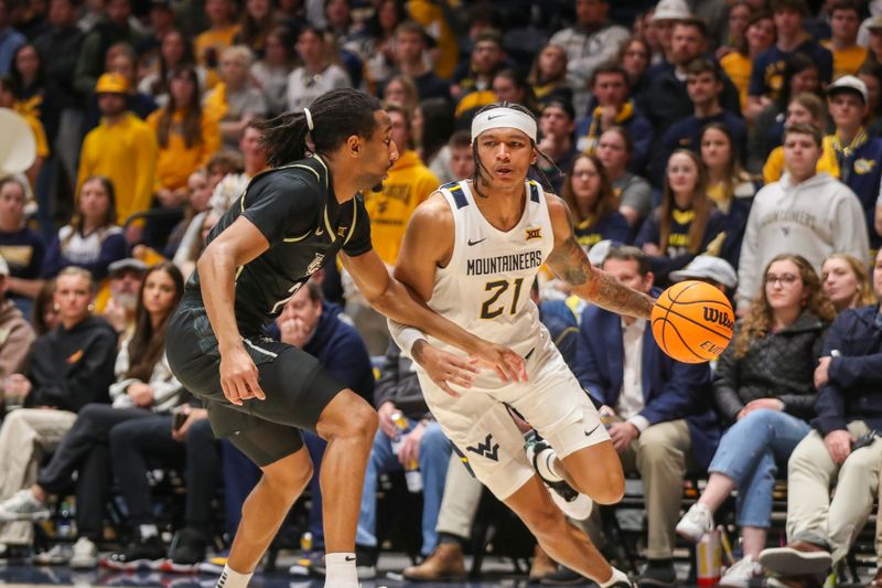 Feb 20, 2024; Morgantown, West Virginia, USA; West Virginia Mountaineers guard RaeQuan Battle (21) drives baseline against UCF Knights guard Shemarri Allen (2) during the second half at WVU Coliseum. Mandatory Credit: Ben Queen-USA TODAY Sports