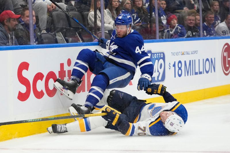 Oct 24, 2024; Toronto, Ontario, CAN; Toronto Maple Leafs defenseman Morgan Rielly (44) and St. Louis Blues forward Oskar Sundqvist (70) collide at the boards during the second period at Scotiabank Arena. Mandatory Credit: John E. Sokolowski-Imagn Images