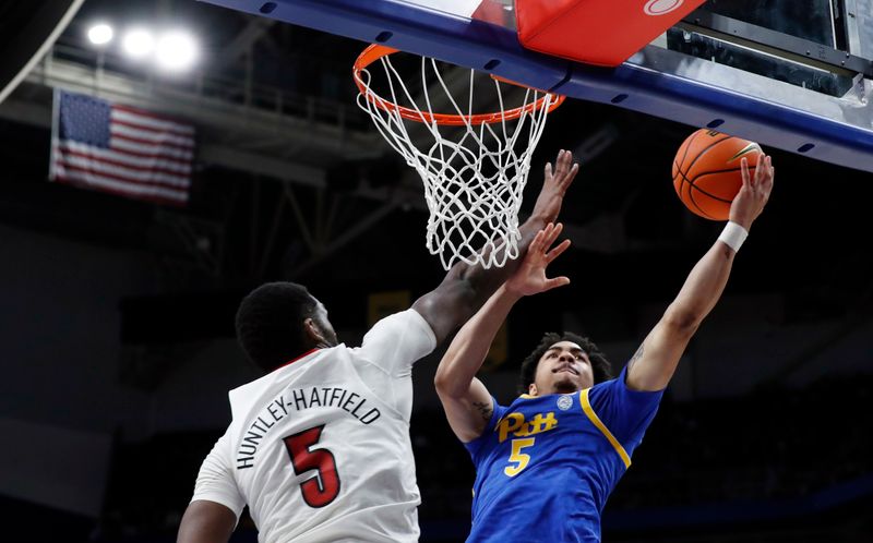 Feb 17, 2024; Pittsburgh, Pennsylvania, USA;  Pittsburgh Panthers guard Ishmael Leggett (5) goes to the basket against Louisville Cardinals forward Brandon Huntley-Hatfield (5) during the second half at the Petersen Events Center. Pittsburgh won 86-59. Mandatory Credit: Charles LeClaire-USA TODAY Sports