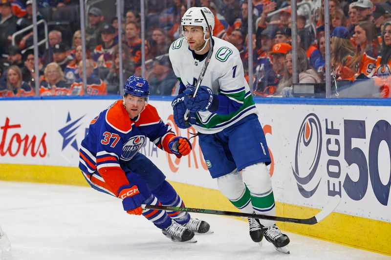 Apr 13, 2024; Edmonton, Alberta, CAN; Vancouver Canucks defensemen Carson Soucy (7) and Edmonton Oilers forward Warren Foegele (37) chase a loose puck during the first period at Rogers Place. Mandatory Credit: Perry Nelson-USA TODAY Sports