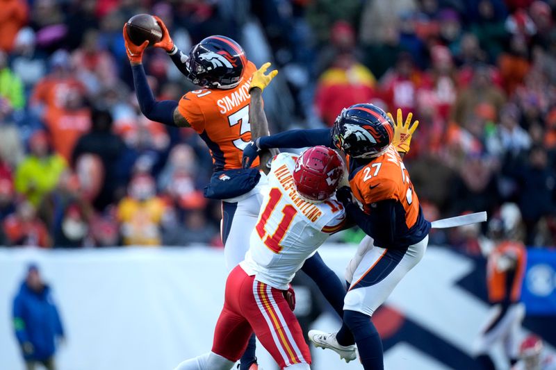 Denver Broncos safety Justin Simmons, left, intercepts a pass intended for Kansas City Chiefs wide receiver Marquez Valdes-Scantling (11) as Broncos cornerback Damarri Mathis (27) gets in on the play during the second half of an NFL football game Sunday, Oct. 29, 2023, in Denver. (AP Photo/David Zalubowski)