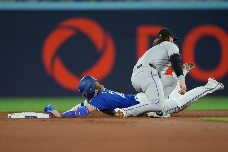 Apr 14, 2024; Toronto, Ontario, CAN; Toronto Blue Jays designated hitter Justin Turner (2) gets caught stealing second base by Colorado Rockies second baseman Brendan Rodgers (7) during the first inning at Rogers Centre. Mandatory Credit: John E. Sokolowski-USA TODAY Sports