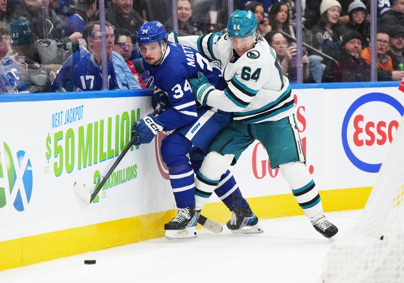 Jan 9, 2024; Toronto, Ontario, CAN; Toronto Maple Leafs center Auston Matthews (34) battles for the puck along the boards with San Jose Sharks center Mikael Granlund (64) during the third period at Scotiabank Arena. Mandatory Credit: Nick Turchiaro-USA TODAY Sports