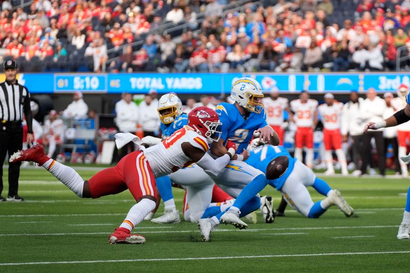 Los Angeles Chargers quarterback Easton Stick, right, fumbles the ball as he is sacked by Kansas City Chiefs defensive end Charles Omenihu, left, during the first half of an NFL football game, Sunday, Jan. 7, 2024, in Inglewood, Calif. The ball was recovered by Kansas City Chiefs safety Mike Edwards, before he ran it back for a touchdown on the play. (AP Photo/Mark J. Terrill)