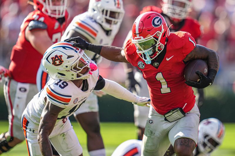 Oct 5, 2024; Athens, Georgia, USA; Georgia Bulldogs running back Trevor Etienne (1) delivers a straight arm to Auburn Tigers safety Sylvester Smith (19) during the first half at Sanford Stadium. Mandatory Credit: Dale Zanine-Imagn Images