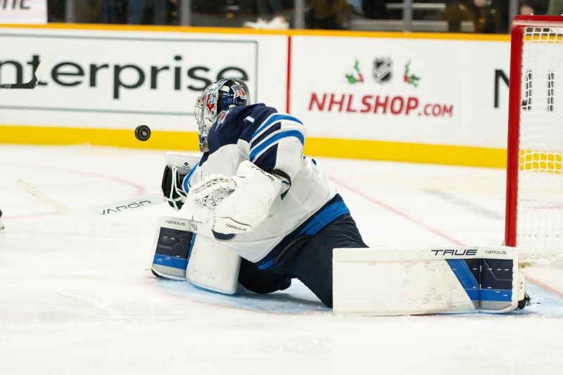 Nov 23, 2024; Nashville, Tennessee, USA;  Winnipeg Jets goaltender Eric Comrie (1) blocks the puck against the Nashville Predators during the third period at Bridgestone Arena. Mandatory Credit: Steve Roberts-Imagn Images