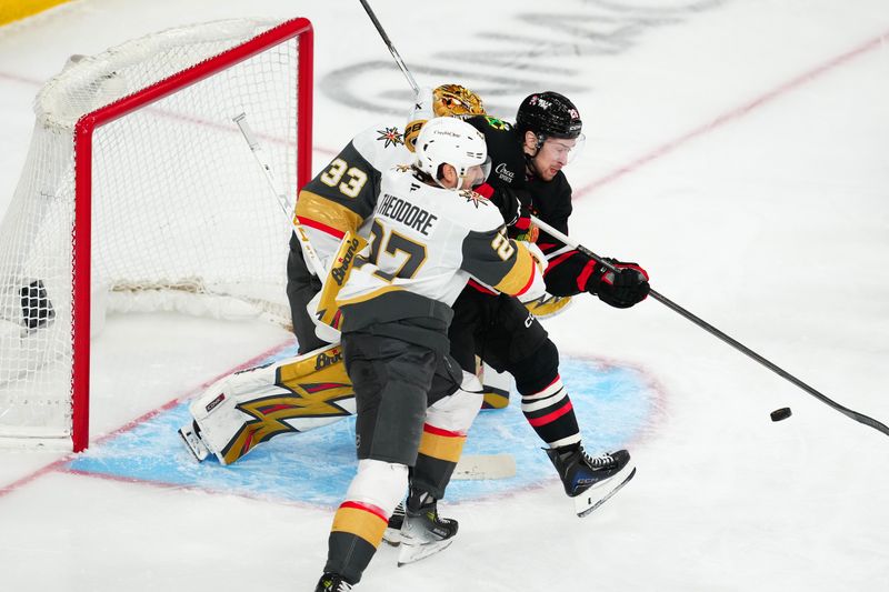 Mar 14, 2026; Las Vegas, Nevada, USA; Chicago Blackhawks left wing Andrew Mangiapane (26) is checked by Vegas Golden Knights defenseman Shea Theodore (27) while attempting to deflect the puck towards goaltender Adin Hill (33) during the third period at T-Mobile Arena. Mandatory Credit: Stephen R. Sylvanie-Imagn Images