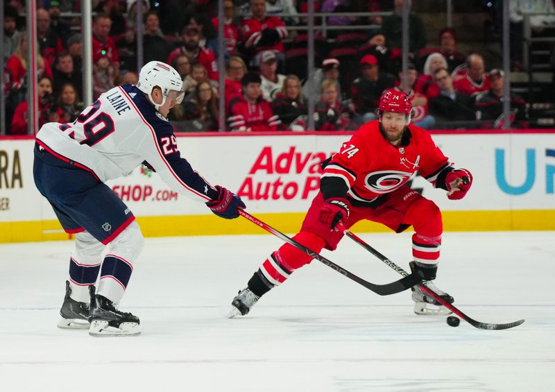 Nov 26, 2023; Raleigh, North Carolina, USA; Columbus Blue Jackets right wing Patrik Laine (29) makes a pass against Carolina Hurricanes defenseman Jaccob Slavin (74) during the first period at PNC Arena. Mandatory Credit: James Guillory-USA TODAY Sports