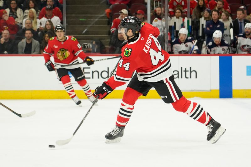 Dec 1, 2024; Chicago, Illinois, USA; Chicago Blackhawks defenseman Wyatt Kaiser (44) shoots the puck against the Columbus Blue Jackets during the first period at United Center. Mandatory Credit: David Banks-Imagn Images