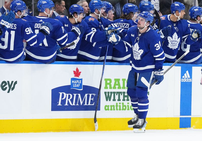 Dec 9, 2023; Toronto, Ontario, CAN; Toronto Maple Leafs center Auston Matthews (34) celebrates at the bench after scoring a goal against the Nashville Predators during the second period at Scotiabank Arena. Mandatory Credit: Nick Turchiaro-USA TODAY Sports