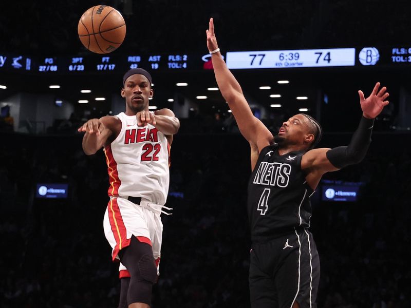 NEW YORK, NEW YORK - JANUARY 15:  Jimmy Butler #22 of the Miami Heat passes against Dennis Smith Jr. #4 of the Brooklyn Nets during their game at Barclays Center on January 15, 2024 in New York City.   User expressly acknowledges and agrees that, by downloading and or using this photograph, User is consenting to the terms and conditions of the Getty Images License Agreement.  (Photo by Al Bello/Getty Images)