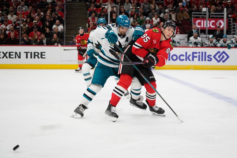 Oct 17, 2024; Chicago, Illinois, USA; Chicago Blackhawks right wing Ilya Mikheyev (95) and San Jose Sharks defenseman Mario Ferraro (38) go for the puck during the third period at United Center. Mandatory Credit: David Banks-Imagn Images