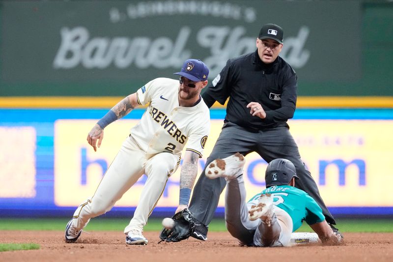 Apr 6, 2024; Milwaukee, Wisconsin, USA;  Seattle Mariners first baseman Dylan Moore (25) is tagged out while trying to steal second base by Milwaukee Brewers second baseman Brice Turang (2) during the sixth inning at American Family Field. Mandatory Credit: Jeff Hanisch-USA TODAY Sports
