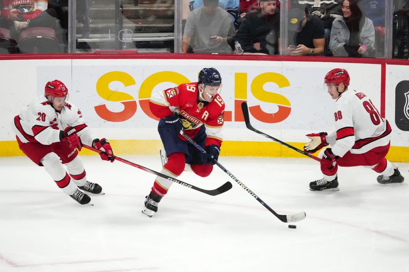 Nov 10, 2023; Sunrise, Florida, USA; Florida Panthers left wing Matthew Tkachuk (19) controls the puck between Carolina Hurricanes center Sebastian Aho (20) and center Martin Necas (88) during the third period at Amerant Bank Arena. Mandatory Credit: Jasen Vinlove-USA TODAY Sports