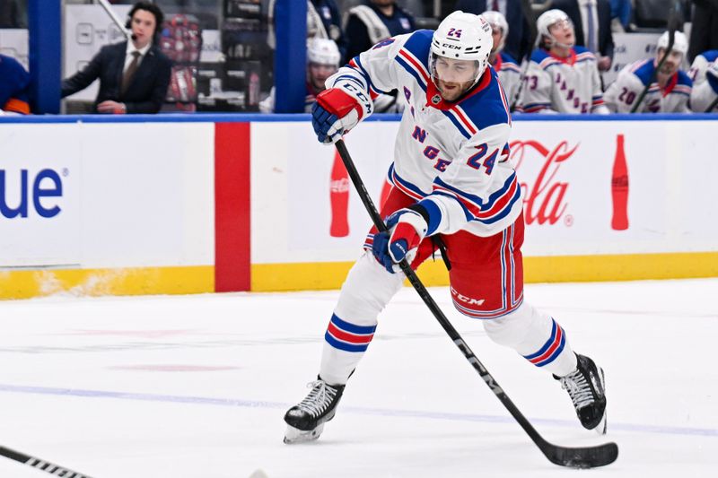 Apr 10, 2025; Elmont, New York, USA;  New York Rangers defenseman Carson Soucy (24) attempts a shot against the New York Islanders during the first period at UBS Arena. Mandatory Credit: Dennis Schneidler-Imagn Images