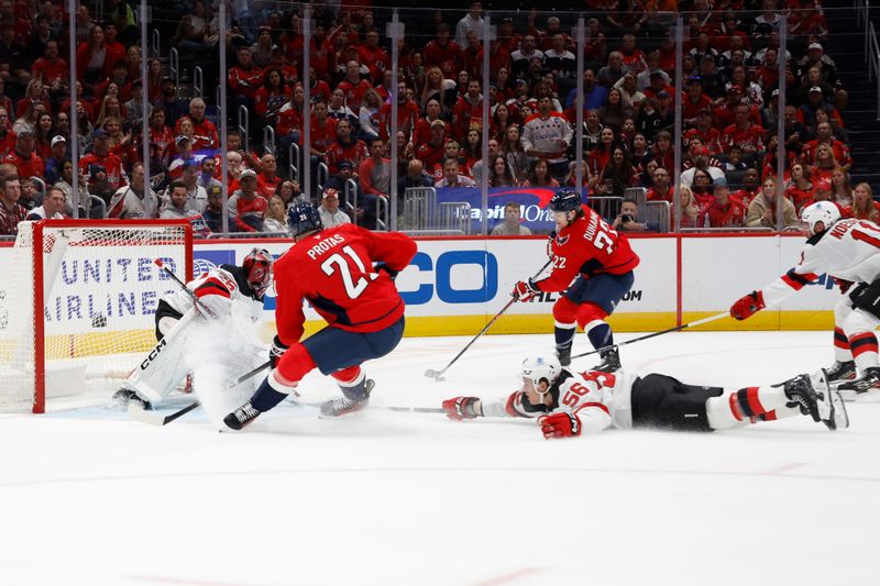 Oct 12, 2024; Washington, District of Columbia, USA; Washington Capitals right wing Brandon Duhaime (22) attempts to pass the puck to Capitals center Aliaksei Protas (21) as New Jersey Devils left wing Erik Haula (56) defends in the first period at Capital One Arena. Mandatory Credit: Geoff Burke-Imagn Images