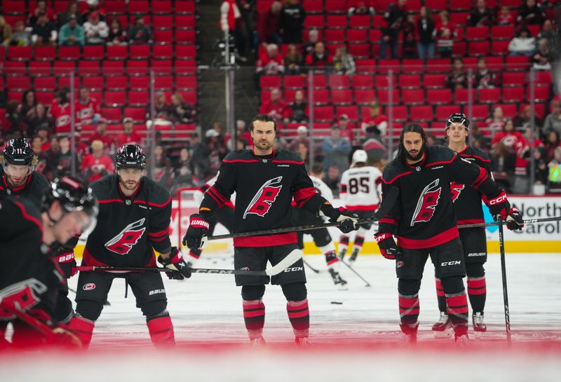 Nov 16, 2024; Raleigh, North Carolina, USA;  Carolina Hurricanes defenseman Shayne Gostisbehere (4) left wing William Carrier (28) and defenseman Jalen Chatfield (5) look on during the warmups before the game against the Ottawa Senators at Lenovo Center. Mandatory Credit: James Guillory-Imagn Images