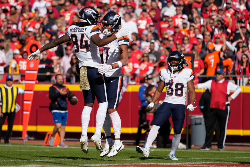 Denver Broncos wide receiver Devaughn Vele (17) is congratulated by Lil'Jordan Humphrey (84) and Jaleel McLaughlin (38) after scoring during the first half of an NFL football game against the Kansas City Chiefs Sunday, Nov. 10, 2024, in Kansas City, Mo. (AP Photo/Ed Zurga)