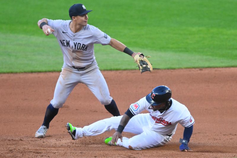 Apr 13, 2024; Cleveland, Ohio, USA; New York Yankees shortstop Anthony Volpe (11) turns a double play beside Cleveland Guardians designated hitter Jose Ramirez (11) in the fourth inning at Progressive Field. Mandatory Credit: David Richard-USA TODAY Sports