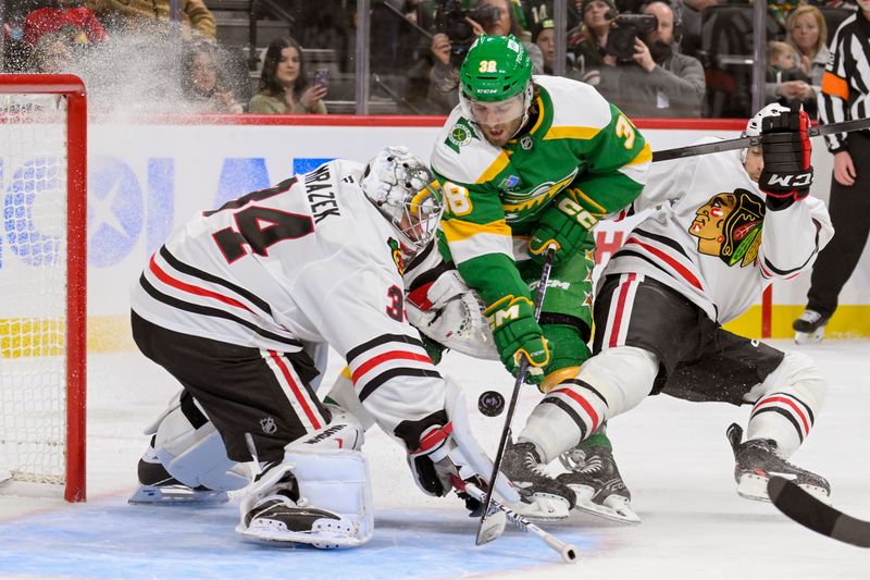 Nov 29, 2024; Saint Paul, Minnesota, USA;  Minnesota Wild forward Ryan Hartman (38) battles for a rebound in front of Chicago Blackhawks goalie Petr Mrazek (34) as defenseman Wyatt Kaiser (44) defends during the second period at Xcel Energy Center. Mandatory Credit: Nick Wosika-Imagn Images