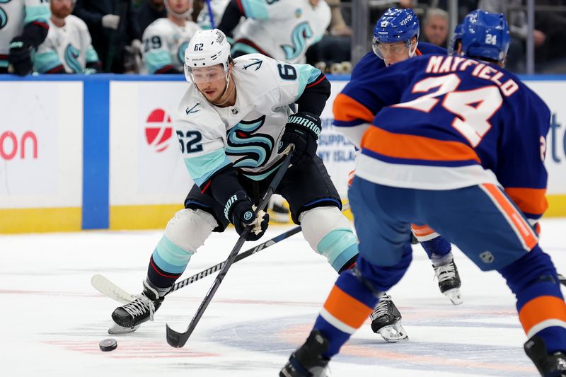 Dec 5, 2024; Elmont, New York, USA; Seattle Kraken defenseman Brandon Montour (62) skates with the puck against New York Islanders left wing Anders Lee (27) and defenseman Scott Mayfield (24) during the first period at UBS Arena. Mandatory Credit: Brad Penner-Imagn Images