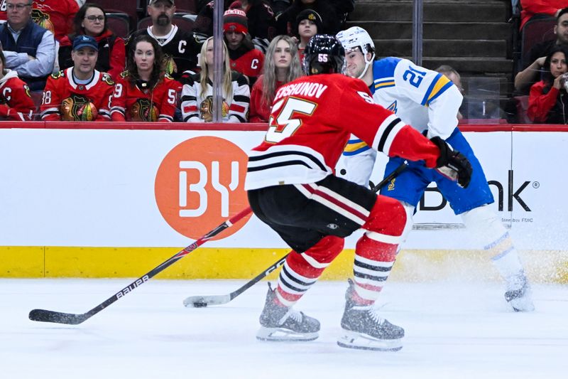 Jan 7, 2026; Chicago, Illinois, USA; St. Louis Blues right wing Jimmy Snuggerud (21) passes the puck away from Chicago Blackhawks defenseman Artyom Levshunov (55) during the first period at the United Center. Mandatory Credit: Matt Marton-Imagn Images
