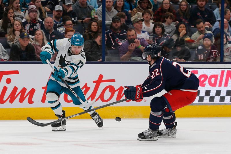 Mar 16, 2024; Columbus, Ohio, USA; Columbus Blue Jackets defenseman Jake Bean (22) deflects the shot attempt of San Jose Sharks center Thomas Bordeleau (17) during the first period at Nationwide Arena. Mandatory Credit: Russell LaBounty-USA TODAY Sports