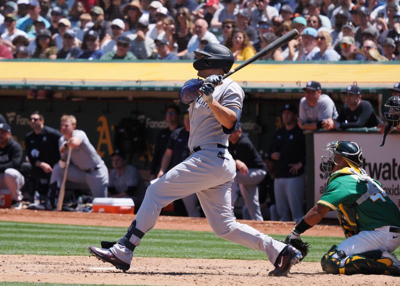 Jun 29, 2023; Oakland, California, USA; New York Yankees right fielder Giancarlo Stanton (27) hits a two-run RBI double against the Oakland Athletics during the sixth inning at Oakland-Alameda County Coliseum. Mandatory Credit: Kelley L Cox-USA TODAY Sports