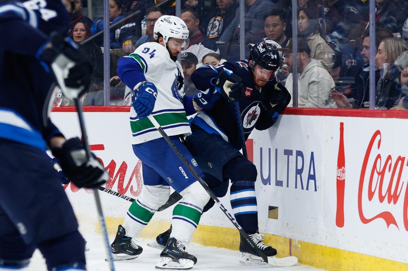 Apr 18, 2024; Winnipeg, Manitoba, CAN;  Winnipeg Jets defenseman Dylan Samberg (54) battles for the puck against Vancouver Canucks forward Phillip Di Giuseppe (34) during the first period at Canada Life Centre. Mandatory Credit: Terrence Lee-USA TODAY Sports