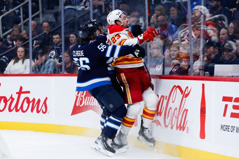 Sep 27, 2025; Winnipeg, Manitoba, CAN;  Winnipeg Jets defenseman Luke Schenn (5) and Winnipeg Jets defenseman Kale Clague (56) board Calgary Flames forward Justin Kirkland (23) during the first period at Canada Life Centre. Mandatory Credit: Terrence Lee-Imagn Images