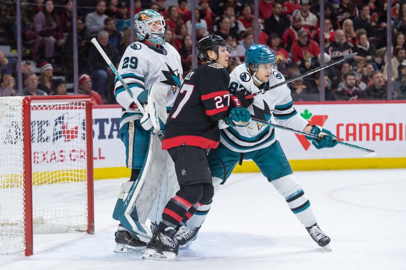 Jan 13, 2024; Ottawa, Ontario, CAN; Ottawa Senators left wing Parker Kelly (27) battles with San Jose Sharks defenseman Nikita Okhotiuk(83) in front of Sharks goalie Mackenzie Blackwood (29) in the first period at the Canadian Tire Centre. Mandatory Credit: Marc DesRosiers-USA TODAY Sports