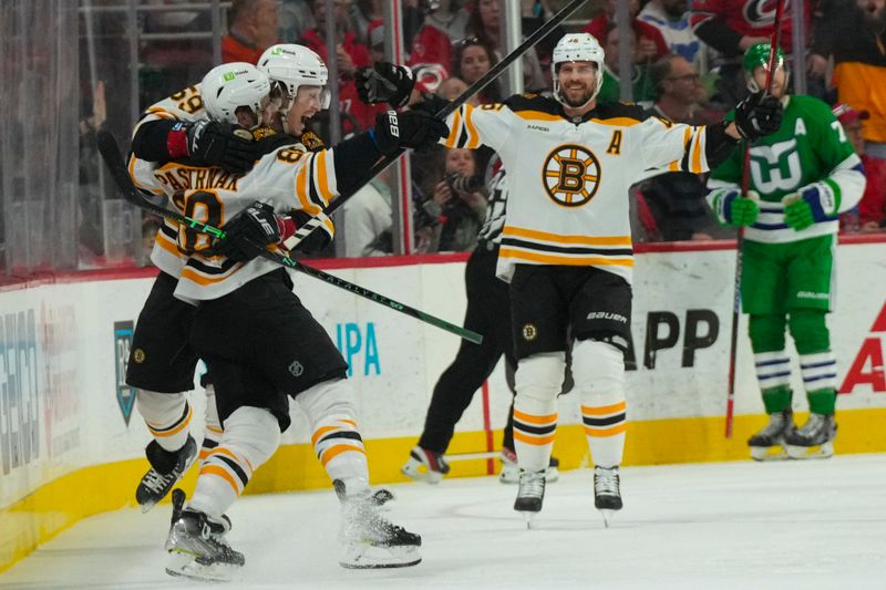 Mar 26, 2023; Raleigh, North Carolina, USA;  Boston Bruins right wing David Pastrnak (88) celebrates his goal with left wing Tyler Bertuzzi (59) and center David Krejci (46) against the Carolina Hurricanes during the first period at PNC Arena. Mandatory Credit: James Guillory-USA TODAY Sports