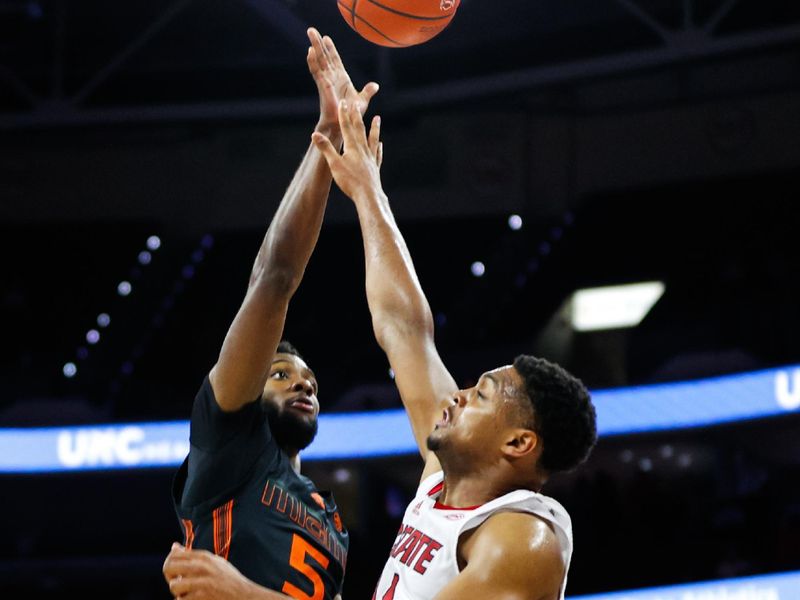 Jan 30, 2024; Raleigh, North Carolina, USA; Miami (Fl) Hurricanes guard Wooga Poplar (5) shoots the ball past North Carolina State Wolfpack guard Casey Morsell (14) the ball during the second half  at PNC Arena. Mandatory Credit: Jaylynn Nash-USA TODAY Sports