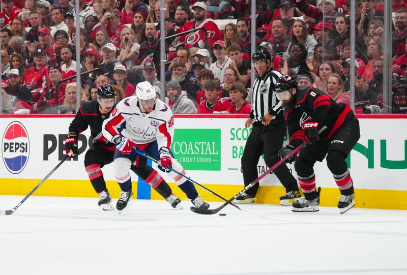 May 10, 2025; Raleigh, North Carolina, USA; Washington Capitals left wing Pierre-Luc Dubois (80) controls the puck against Carolina Hurricanes defenseman Dmitry Orlov (7) and defenseman Brent Burns (8) during the first period in game three of the second round of the 2025 Stanley Cup Playoffs at Lenovo Center. Mandatory Credit: James Guillory-Imagn Images