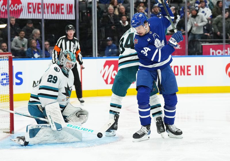 Jan 9, 2024; Toronto, Ontario, CAN; Toronto Maple Leafs center Auston Matthews (34) battles for the pick with San Jose Sharks defenseman Jan Rutta (84) in front of  goaltender Mackenzie Blackwood (29) during the third period at Scotiabank Arena. Mandatory Credit: Nick Turchiaro-USA TODAY Sports