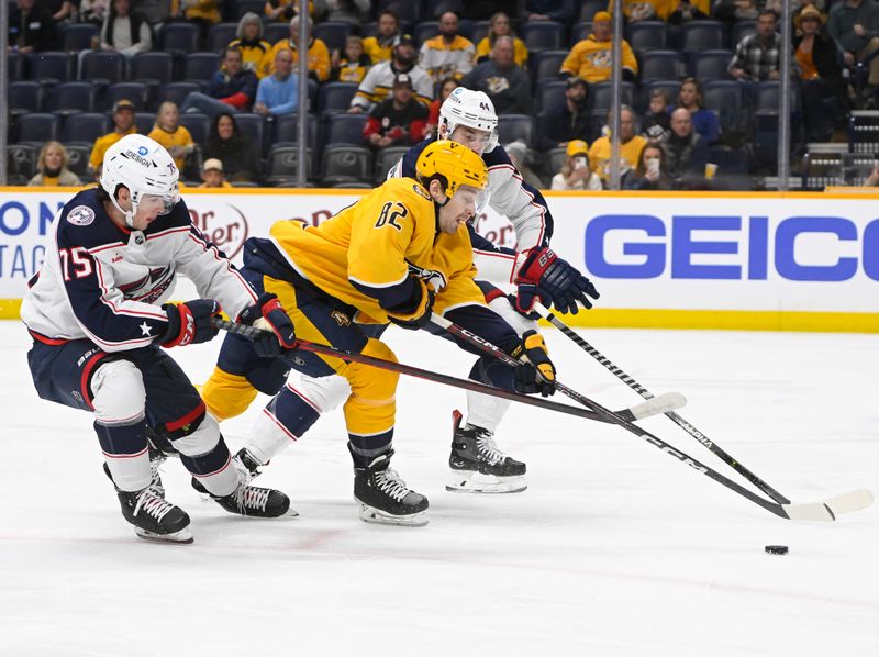 Jan 17, 2023; Nashville, Tennessee, USA;  Nashville Predators center Tommy Novak (82) splits Columbus Blue Jackets defenseman Tim Berni (75) and defenseman Erik Gudbranson (44) during the first period at Bridgestone Arena. Mandatory Credit: Steve Roberts-USA TODAY Sports