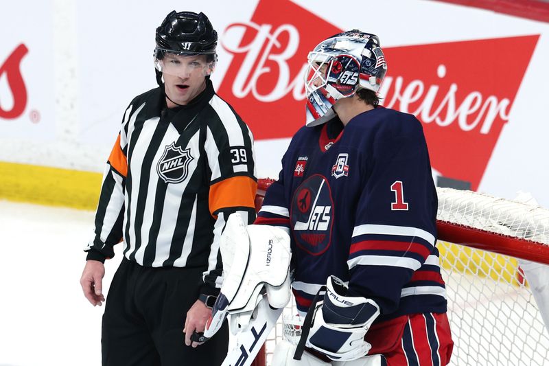 Mar 15, 2026; Winnipeg, Manitoba, CAN; Referee Brandon Blandina (39) talk with Winnipeg Jets goaltender Eric Comrie (1) during a game against the St. Louis Blues at Canada Life Centre. Mandatory Credit: James Carey Lauder-Imagn Images